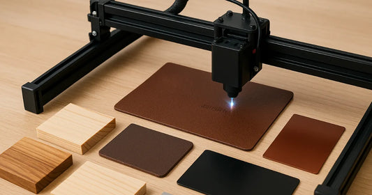Gravure laser sur cuir en cours, avec échantillons de bois, métal et acrylique disposés sur un établi artisanal.