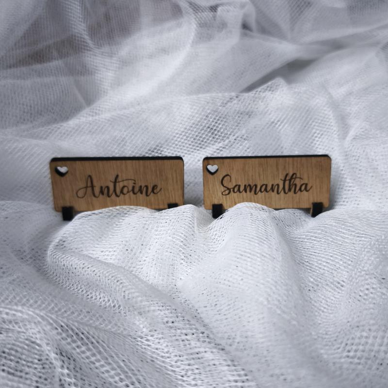 Marque-places en bois personnalisés avec les prénoms Antoine et Samantha, gravés au laser sur un fond en tissu blanc élégant