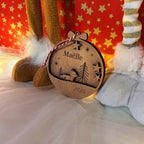 Gros plan de la suspension renard hivernal gravée avec détails fin, étoiles et sapins, gravure laser précise sur bois naturel pour premier Noël bébé