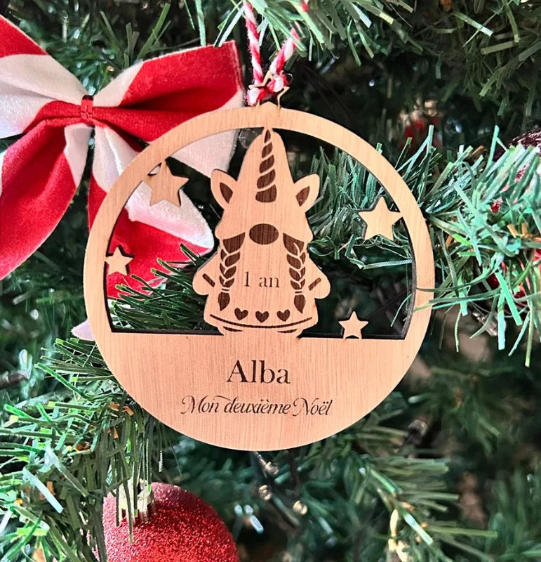 Suspension en bois personnalisée avec lutin licorne, prénom Alba et mention "1 an" pour un deuxième Noël magique, accrochée dans le sapin.
